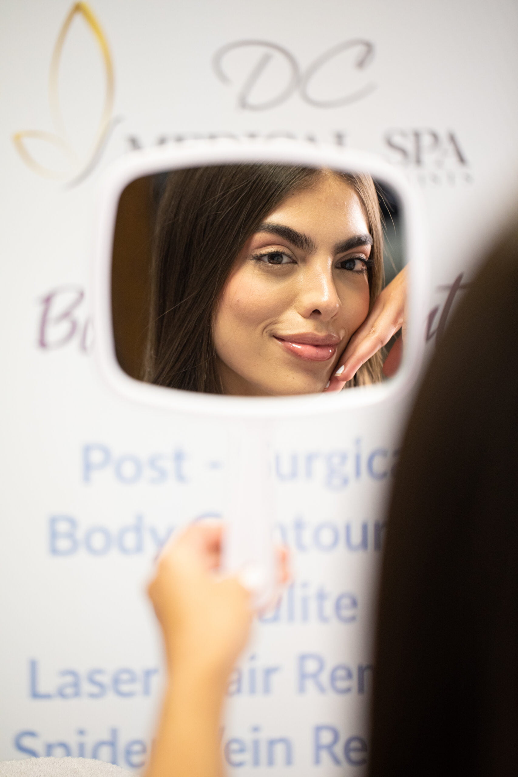 Woman At DC Medical spa looking in the mirror happy happy with her botox